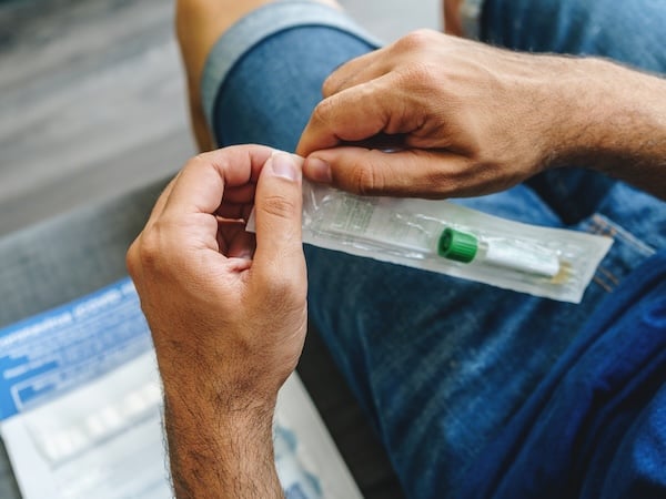 Photo of a man opening a wrapped COVID test.